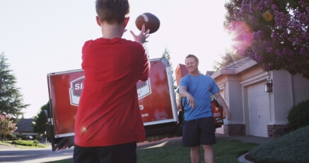 A man and child playing outside with a Sierra Pacific service truck in the driveway.