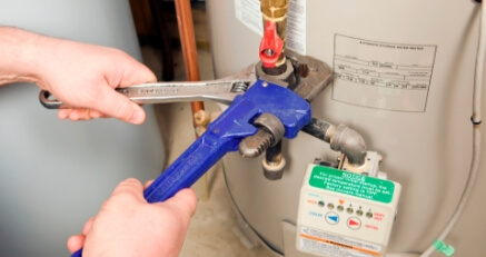 A technicain working on a water heater's plumbing.