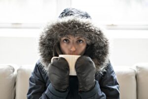 woman-inside-with-parka-on-drinking-from-mug