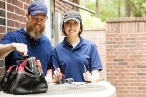 male-and-female-technicians-standing-over-outside-ac-unit