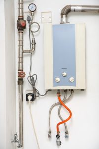 Wall-mounted tankless water heater with connected pipes and wires, representing tankless water heater installation.