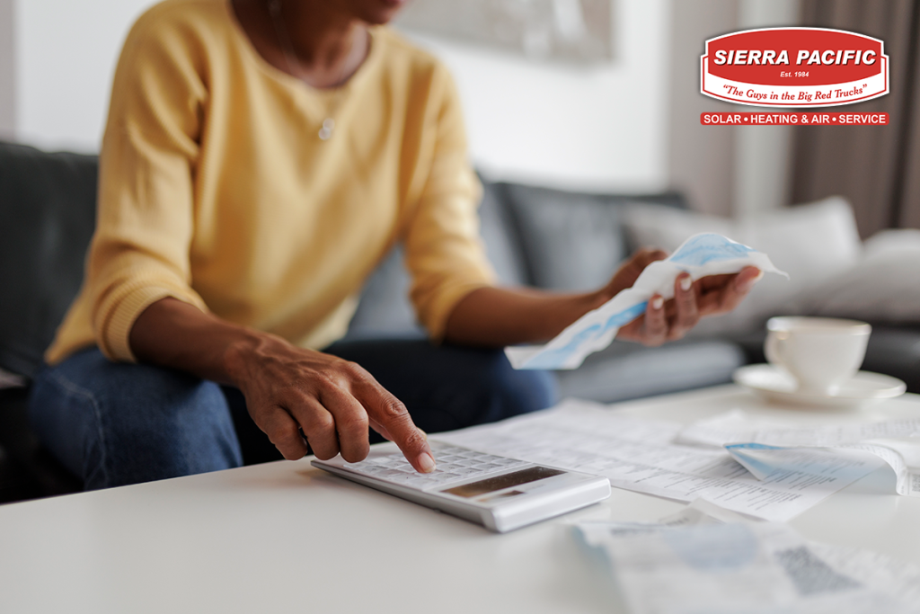 Close up of a mid adult woman checking her energy bills at home, sitting in her living room. She has a worried expression